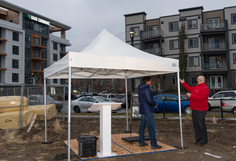 2 people standing under a white tent.