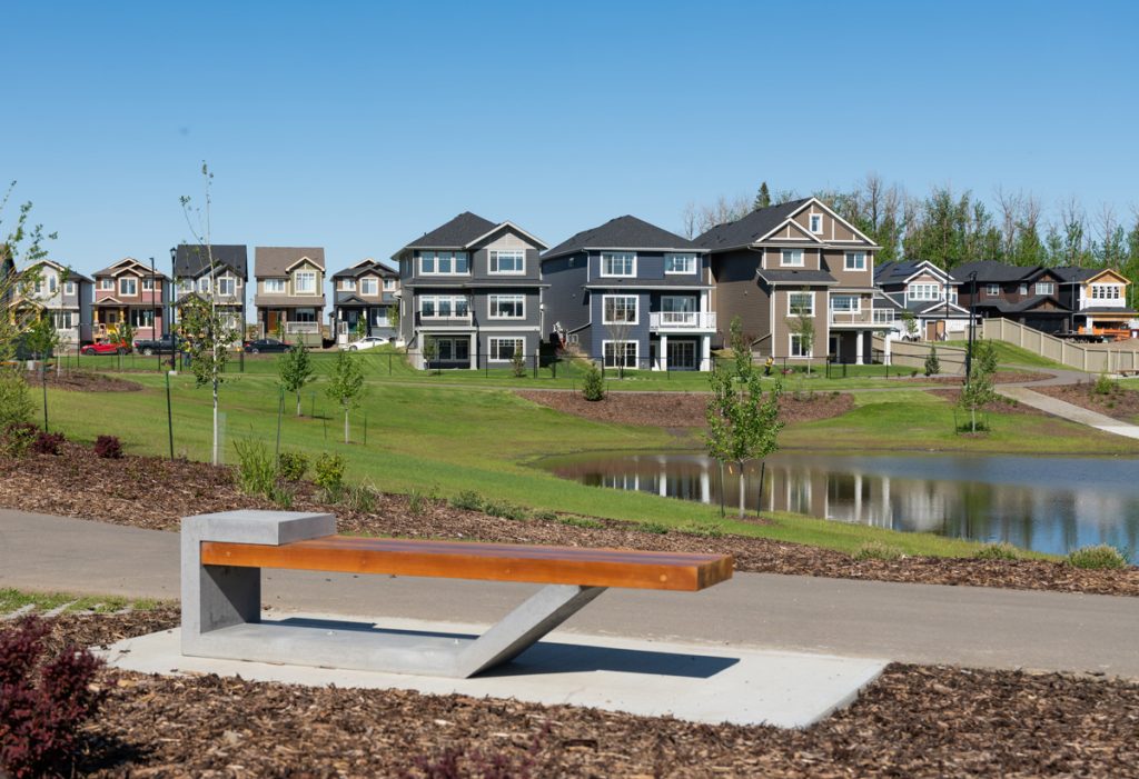 Woodhaven bench with pond and houses in the background.