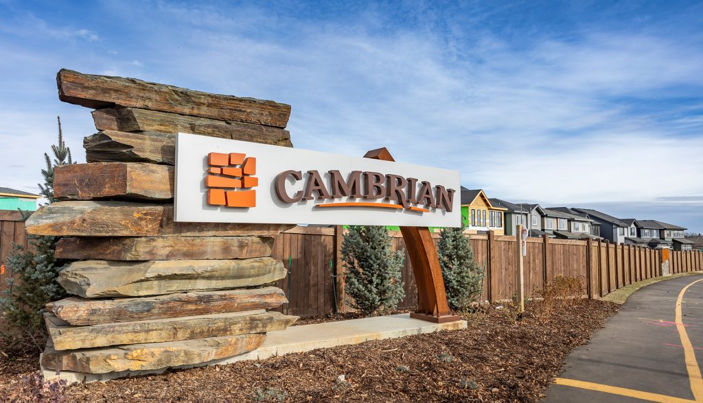 Cambrian sign on stacked stones with fence and houses behind.