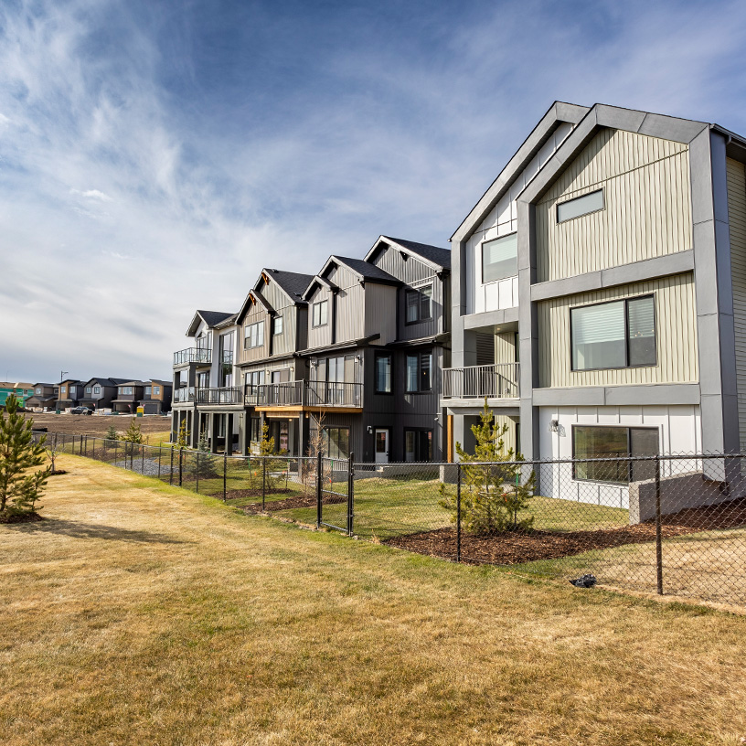 View of houses, grass, and chain fence.