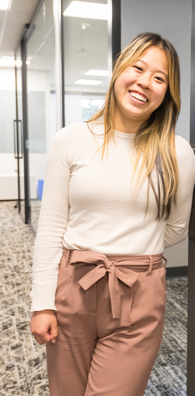 Woman leaning against wall and smiling.