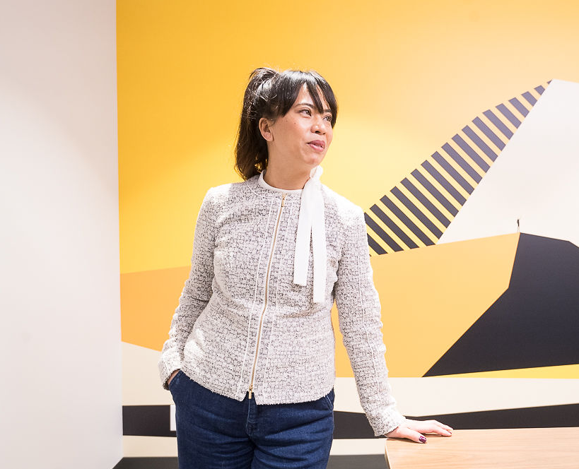 Photo of woman standing in front of wall with unique yellow and black design.