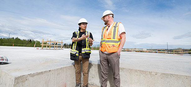 Two construction works standing beside each other in conversation.